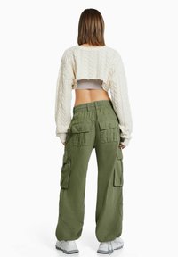 Skuren beige kabelstickad tröja med långa ärmar, parat med olivgröna cargobyxor med flera fickor och elastisk midja.