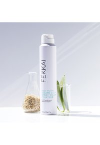 Fekkai Volume Lock Spray in a alto contenitore aerosol bianco con testo nero e turchese. Includere avena in un recipiente di vetro e foglie di aloe.
