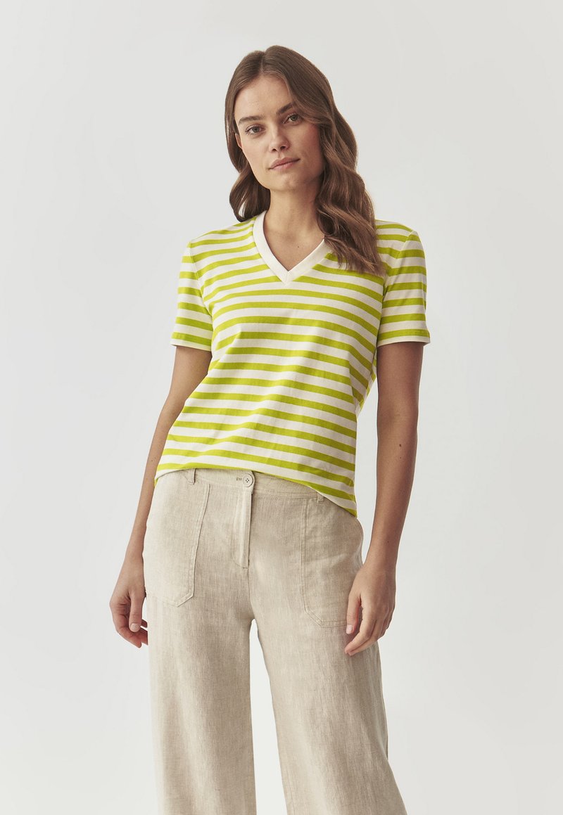 Grøn- og hvidstribet v-hals t-shirt med korte ærmer, lavet af et letvægtsstof, parret med beige linnedbukser.