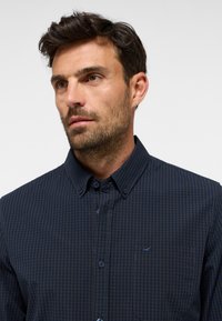 Camicia a scacchi blu navy, con bottoni, realizzata in cotone, presenta una tasca con logo, colletto classico e tessuto testurizzato per un tocco di dettaglio in più.