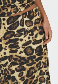 Leopardskinds stof med en blanding af gyldenbrune og sorte pletter. Teksturen ser blød ud, med et glat, flydende design.