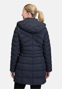 Marineblå quiltet pufferjakke med hætte, der har diagonale syninger og en tætsiddende talje, designet til varme og komfort.