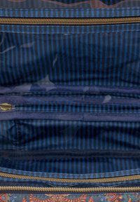 Marineblauwe stoffen tas met binnenin twee compartimenten, een gouden ritssluiting en een gestreept patroon in contrasterende tinten blauw.