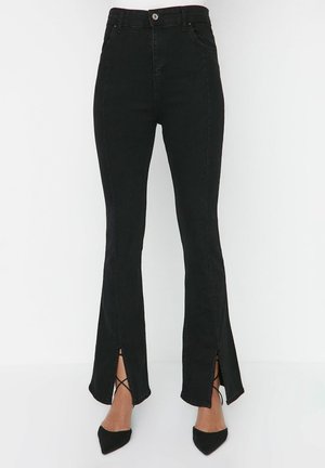 Schwarze hoch taillierte Slim-Fit-Hose mit Frontrissen, getragen mit schwarzen spitzen Pumps.