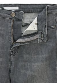 Grå denimjeans med dragkedja, två framfickor och en metallknapp. Tyget har en subtil blekt struktur och sömnadsdetaljer.