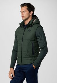 Gilet imbottito verde scuro con chiusura a zip, cappuccio regolabile e tasca laterale con zip; presenta un logo esagonale sul petto.