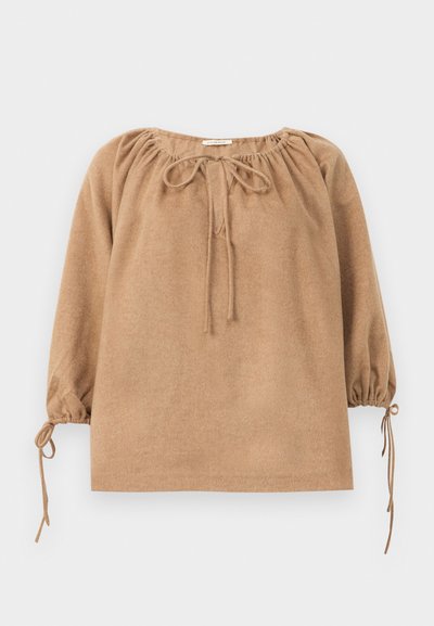 Top din țesătură moale, de culoare brună, cu gât adunat, șnururi pentru strângere și mâneci bufante cu detalii legate la manșete. Croi lejer, design minimal.
