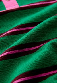 Green textured fabric with horizontal stripes in pink and brown. Features a button detail in a light pink shade.