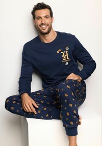 Sudadera navy con logotipo bordado de Hogwarts; pantalones de pijama a juego con símbolos coloridos de Harry Potter y diseños caprichosos. Ajuste cómodo.