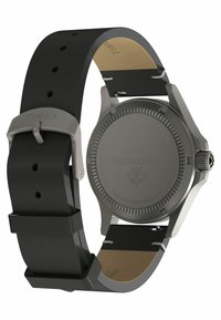 Montre Timex avec un bracelet en silicone noir, boîtier en titane gris, forme ronde, lunette texturée et dos lisse comportant un logo gravé.