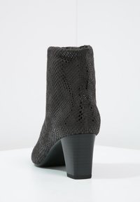 Bottine noire à motif serpent, avec un bout arrondi et un talon bloc élégant; texture lisse et design sans couture.