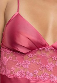 Roze satijnen camisole met delicate kantafwerking en bloemmotieven. Zachte textuur, verstelbare schouderbandjes en een V-halsontwerp.