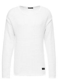 Volný bílý pletený svetr s dlouhými rukávy, kulatým výstřihem a texturovaným vzorem. Na lemu má černou etiketu.