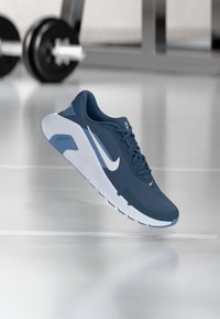 Chaussure de sport bleue avec dessus en mesh respirant, accents blancs, semelle texturée et design incurvé. Idéale pour le sport et un usage quotidien.
