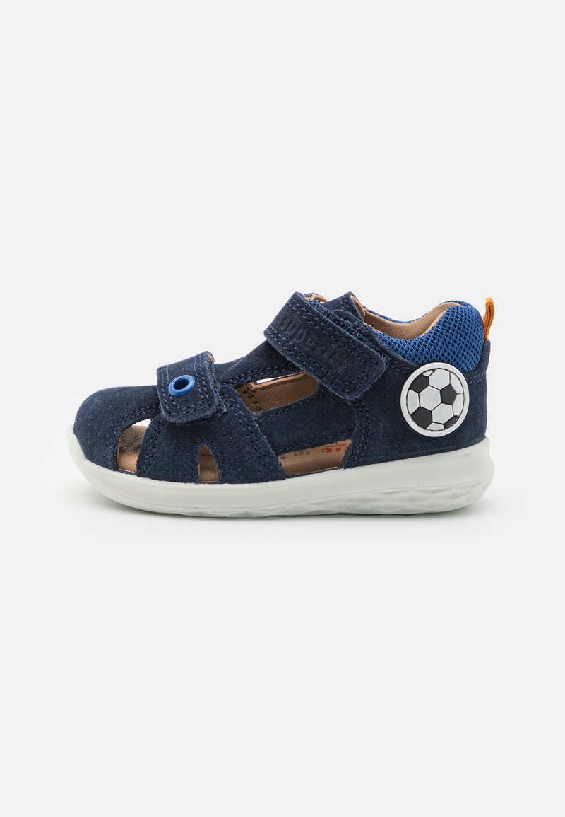 Blå ruskindsandal med udskæringsdesign, dobbelte Velcro-stropper, hvid gummisål og et fodboldmotiv på siden.