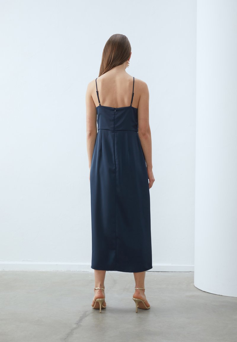 Námořnické saténové šaty s tenkými ramínky, přiléhavým trupem a splývavou sukní. Mají zapínání na knoflíky na zadní straně a dosahují délky do poloviny lýtek.