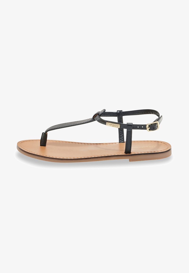 Sandalia de thong de cuero negro con suela plana color marrón. Cuenta con una correa ajustable en el tobillo y detalle de hardware dorado en la correa.