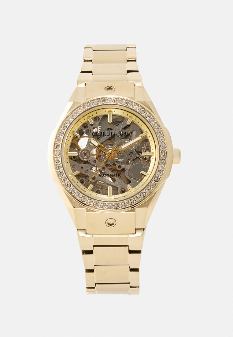 Reloj automático dorado con un dial transparente, engranajes intrincados visibles y un bisel acentuado con rhinestones. Pulsera de metal. Carátula hexagonal.