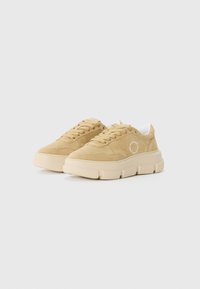 Beige semskede sneakers med en chunky kremfarget såle, med snøring, subtil logo-detalj på siden, og en jevn teksturert overdel.