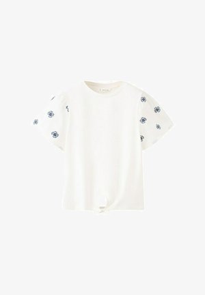 Blouse blanche à manches courtes avec des imprimés floraux marins sur les manches et un petit nœud noué à l'avant.