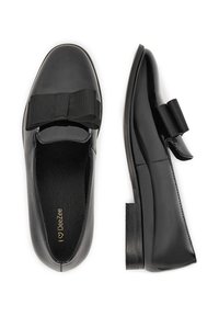 Czarne lakierowane baleriny z wyraźną czarną kokardą z przodu, gładkim wykończeniem, okrągłym noskiem i niskim, skośnym obcasem.