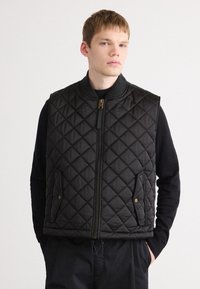 Black quilted vest with a high collar, front zip closure, side pockets, and a textured pattern. Soft fabric with a smooth finish.