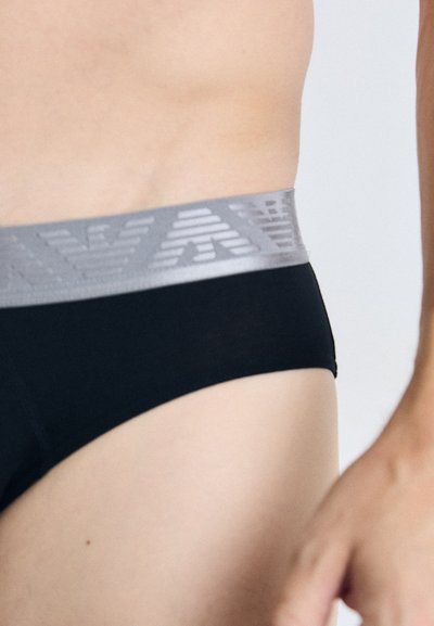 Boxeri negri cu un brâu texturat gri, decorat cu modele geometrice. Materialul pare neted și mulat, având un design cu talie joasă.