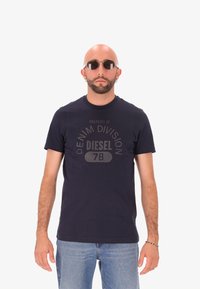 Navyblauwe katoenen t-shirt met ronde hals, korte mouwen en een grijze logo-opdruk met de tekst "EIGENDOM VAN DENIM DIVISION DIESEL 78."