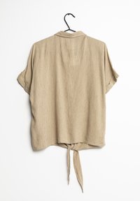 Camiseta de manga corta con cuello, con una textura acanalada y un detalle anudado en la parte trasera. Diseñada con un ajuste holgado y un estilo casual.