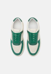 Baskets en cuir vert et crème avec un bout perforé, des accents en daim contrastés et des lacets verts. Semelle plate et col rembourré.