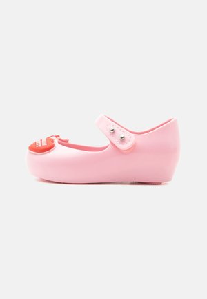 Chaussure bébé Mary Jane rose avec décoration rouge en forme de cœur sur l'avant et bride ajustable avec boutons-pression.