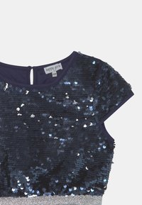 Marineblaues Oberteil, das mit Pailletten bedeckt ist, mit einem runden Halsausschnitt und kurzen Ärmeln. Verfügt über einen Knopfverschluss hinten und einen silbernen Akzent am Saum.