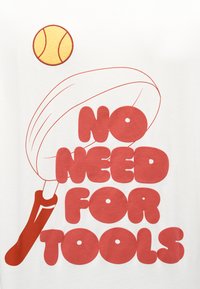 Λευκό μπλουζάκι με έντονο κόκκινο κείμενο που γράφει «ΔΕΝ ΧΡΕΙΑΖΟΝΤΑΙ ΕΡΓΑΛΕΙΑ», με μια κίτρινη μπάλα του τένις από πάνω και ένα παιχνιδιάρικο σχέδιο ρακέτας.