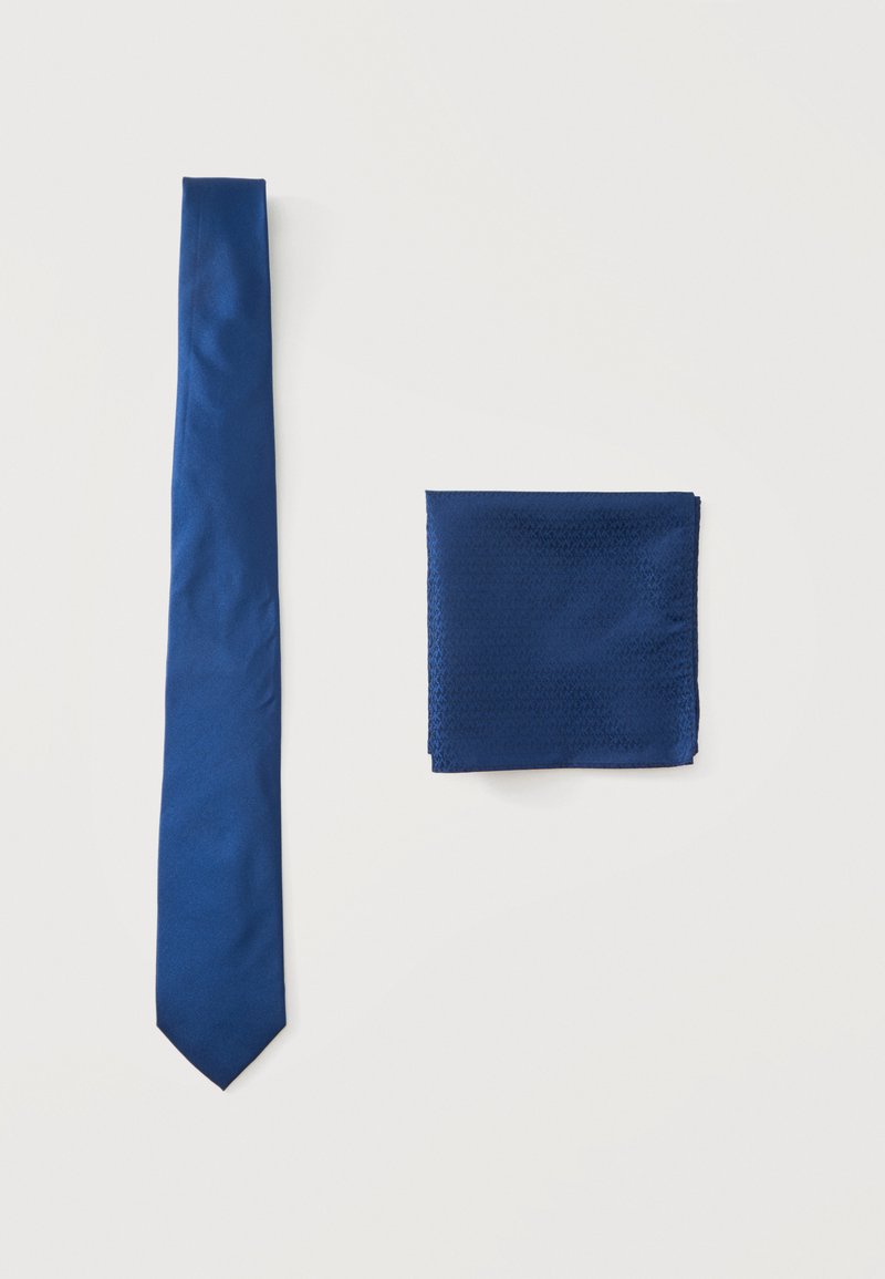 Cravate bleue unie et pochette bleue assortie pliée, présentées sur un fond blanc.
