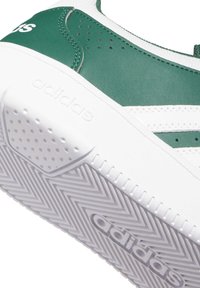 Suela de zapatilla Adidas verde y blanca con patrón texturizado y logo de Adidas en relieve en el costado y la parte inferior del zapato.