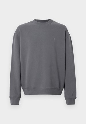 Šedá mikina vyrobená z mäkkého materiálu, s okrúhlym výstrihom, spadnutými ramenami, rebrovanými manžetami a malým logom na hrudi.