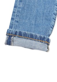 Blue denim jeans leg with a single cuff folded up, showing the inside seam and orange stitching detail.