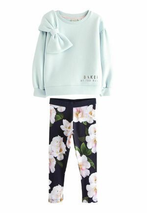 Sudadera de color azul claro con un detalle de lazo en el hombro izquierdo, combinada con leggings negros que presentan patrones florales en rosa y blanco.
