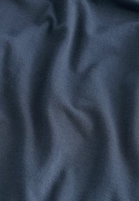 Dunkelblauer Stoff mit glatter Textur, der subtile diagonale Rippungen und leichte Drapierung aufweist. Ideal für Bekleidungs- oder Polsteranwendungen.