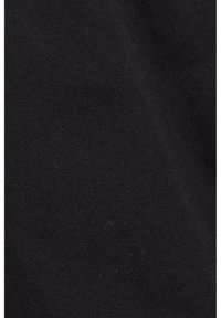 Gros plan d'un tissu noir avec une texture de tissage diagonale visible et des ombres subtiles mettant en valeur les plis.