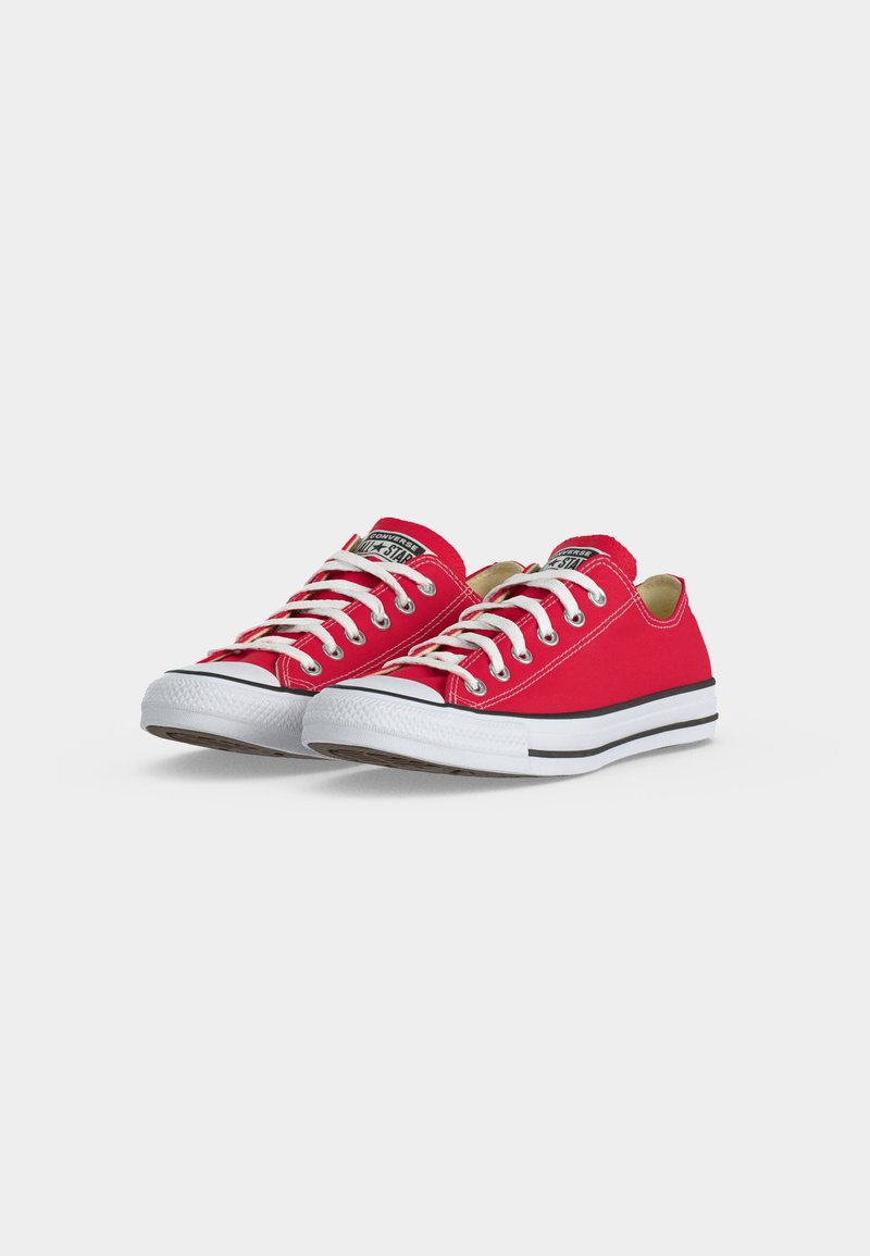 Coppia di sneakers Converse basse rosse con lacci bianchi, puntali in gomma bianchi e suole bianche rigate nere su sfondo bianco.