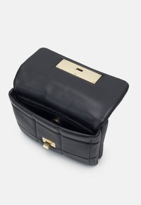 Borsa a mano in pelle nera con design trapuntato, una placca metallica dorata in alto e una chiusura anteriore. L'interno presenta una morbida fodera.