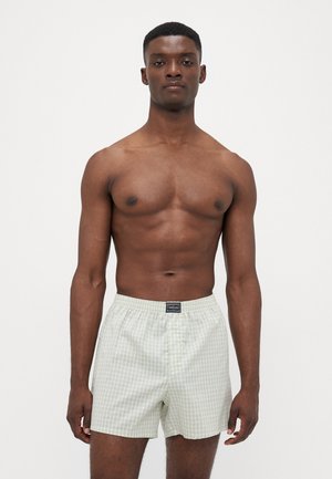 Hellgrüne karierte Boxershorts aus Baumwolle mit einem elastischen Bund und einem Knopfverschluss. Dünner, weicher Stoff mit glatter Textur.