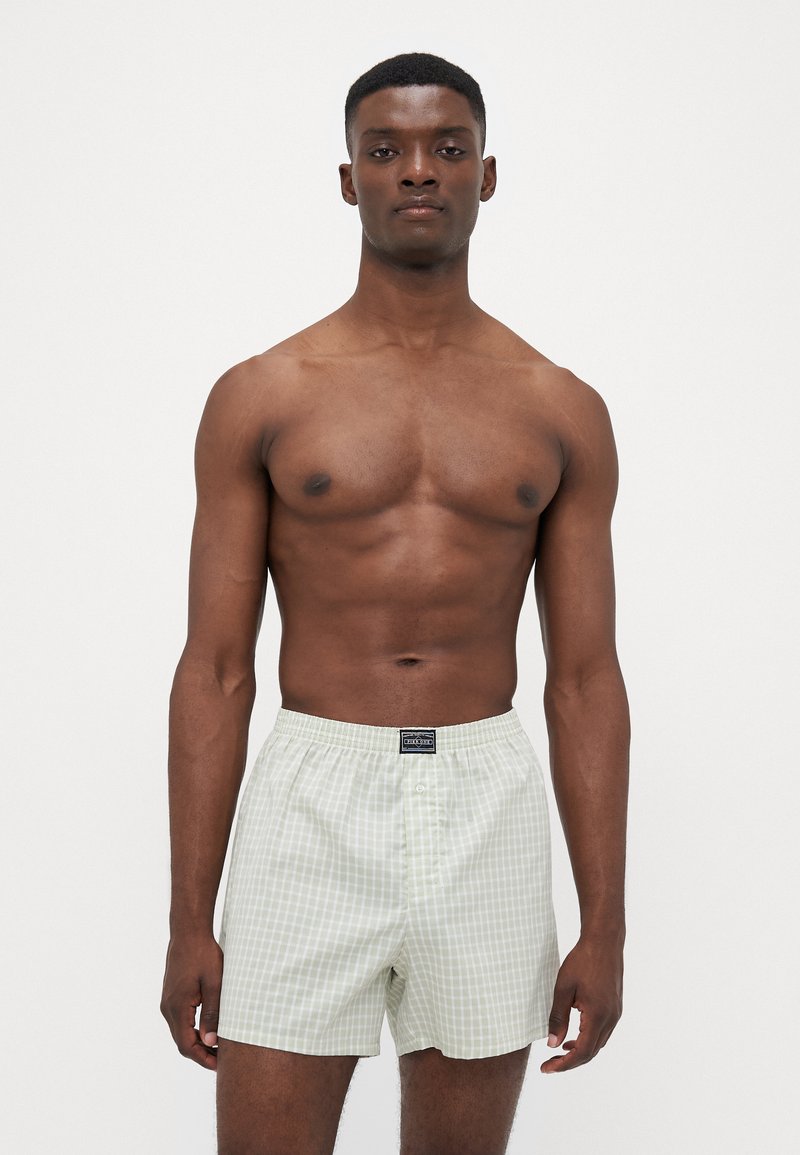 Lysegrøn rutete boxershorts laget av bomull, med elastisk midjebånd og knappestolpe. Tynn, myk stoff med en jevn tekstur.