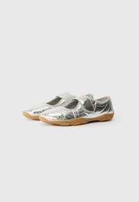 Metallic silver ballet flats with a single elastic strap, rounded toe, and a flexible brown rubber sole. Textured upper surface with stitching details.