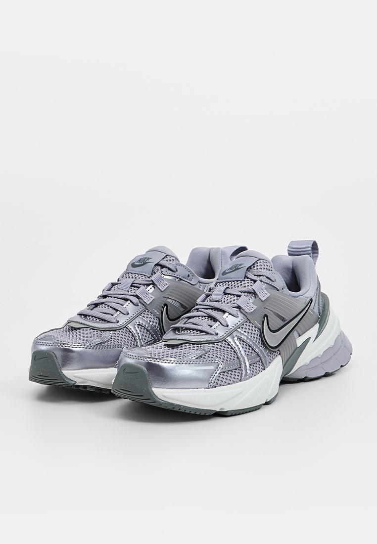 Scarpe da corsa Nike con tomaia in rete grigia e accenti argentati, suola ammortizzata e dettagli testurizzati sul tallone e sui lati.