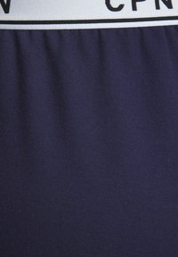 Námorná bavlnená zmesová tkanina, ktorá sa vyznačuje hladkou textúrou a elastickým pásom s potlačeným logom v bielej a čiernej farbe.