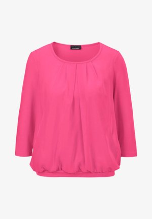 Fuchsia-Oberteil mit dreiviertel Ärmeln und Falten am Ausschnitt, kombiniert mit hellblauen, abgeschnittenen Jeans und grauen Ballerinas.