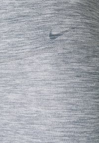 Jasnoszara tkanina sportowa o subtelnej, melanżowej teksturze. Posiada małe, półprzezroczyste logo Nike oraz płaskie szwy.