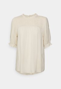 Krämfärgad blus med smockad midja, korta puffärmar och en volangkrage. Mjuk, lättviktig tyg med en fladdrande silhuett.